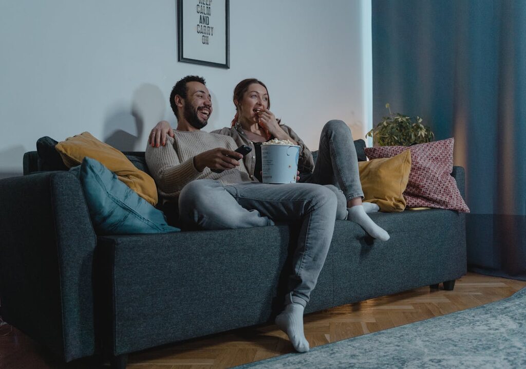 casal no sofá assistindo filme, representando o que é subwoofer
