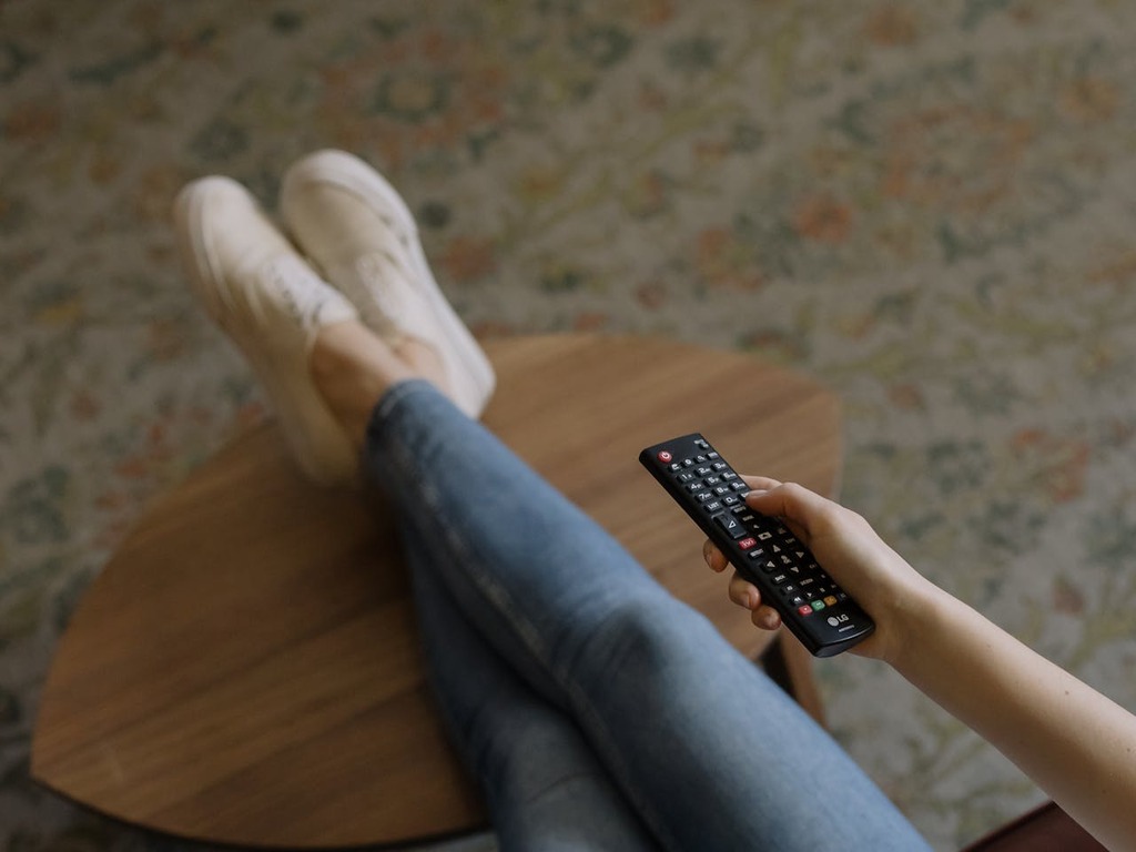 pessoa com controle remoto, representando o sinal de TV digital ou analógico